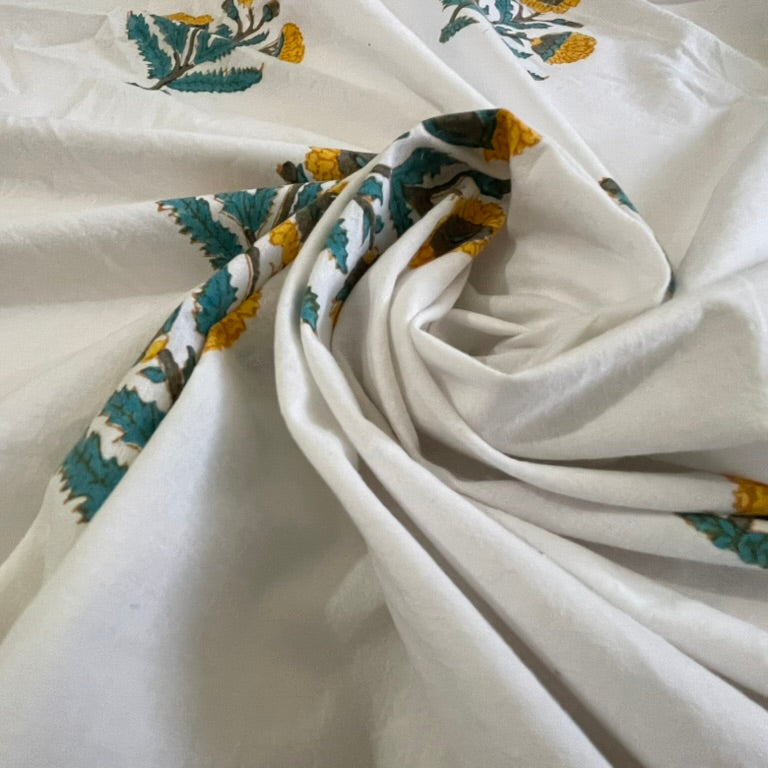 Close-up of white fabric with floral patterns in green and yellow.