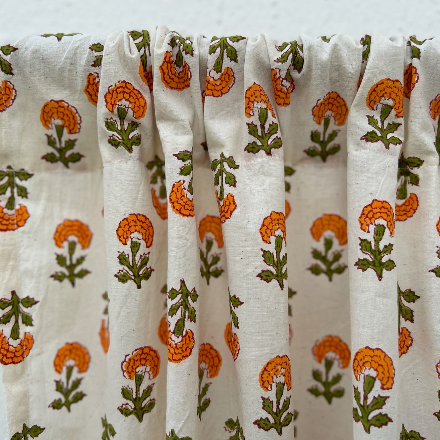 Floral patterned fabric draped over a rod against a white background