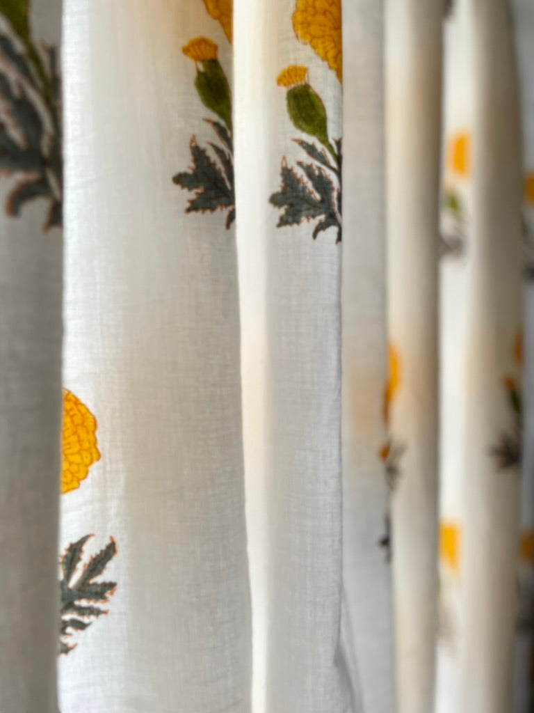 Close-up of a textured fabric with floral patterns in yellow and green on a white background.