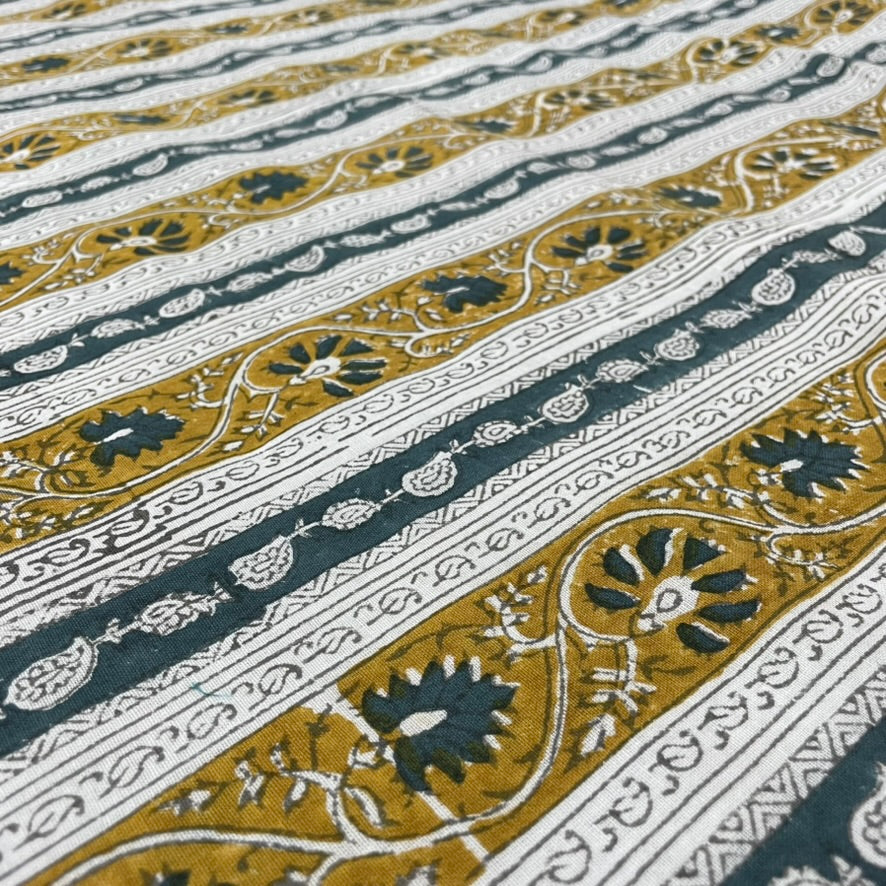 Close-up of a fabric with intricate Teal, gold, and white pattern