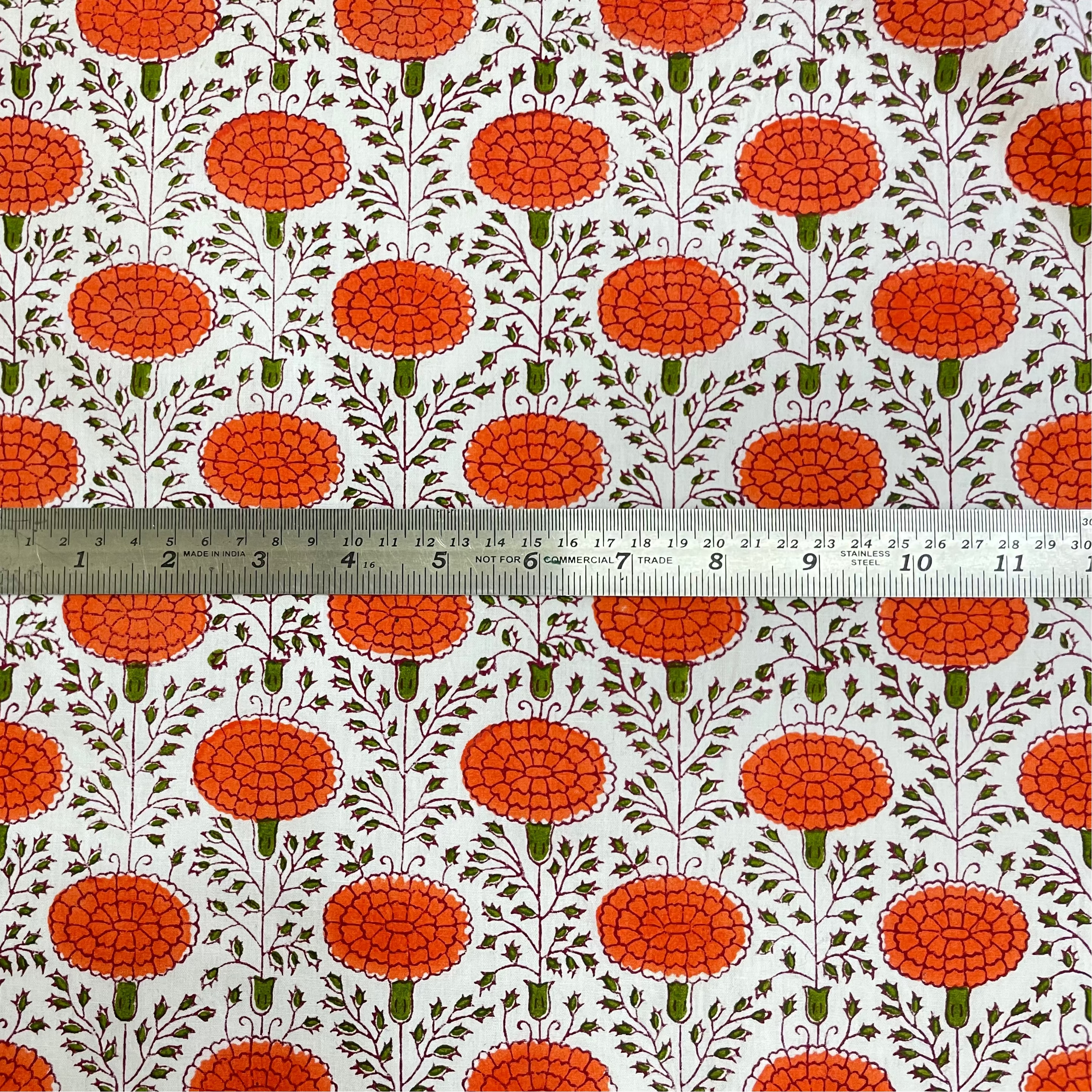 Patterned fabric with orange floral design on a white background, ruler for scale.