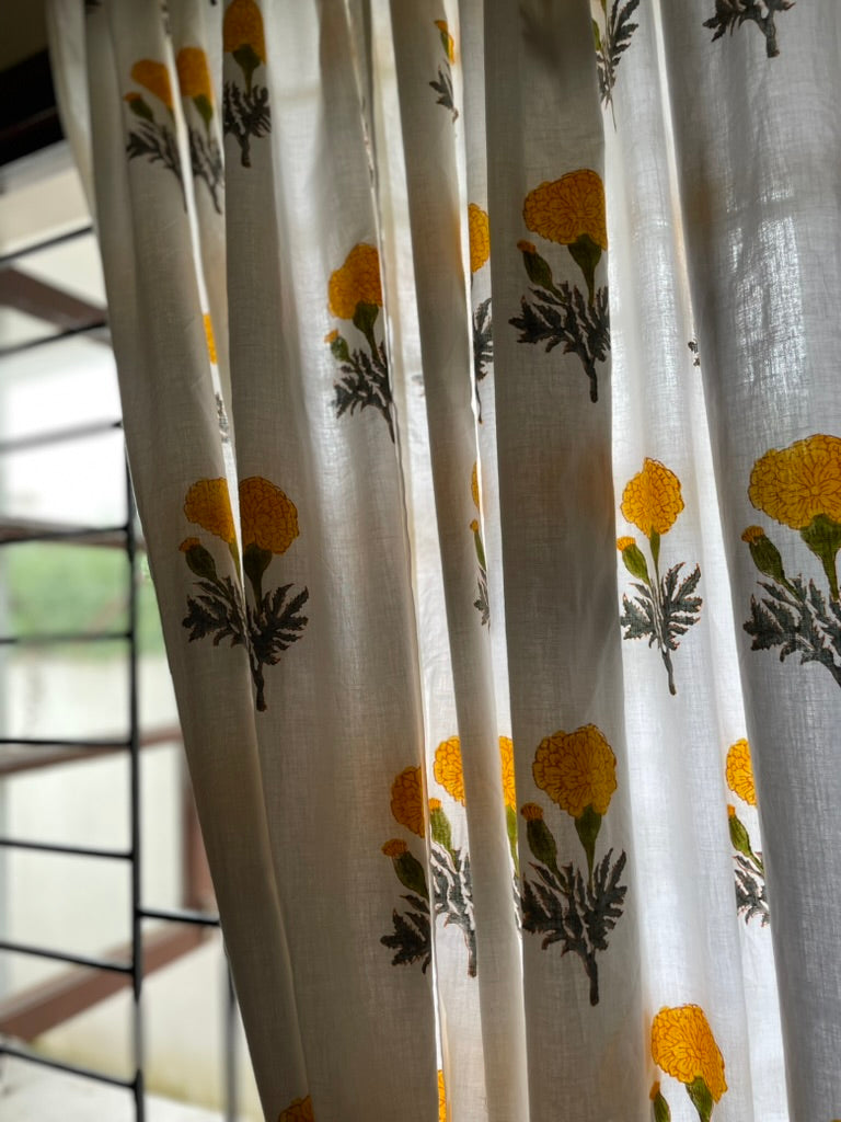 Sheer curtains with floral pattern in a room with a window.