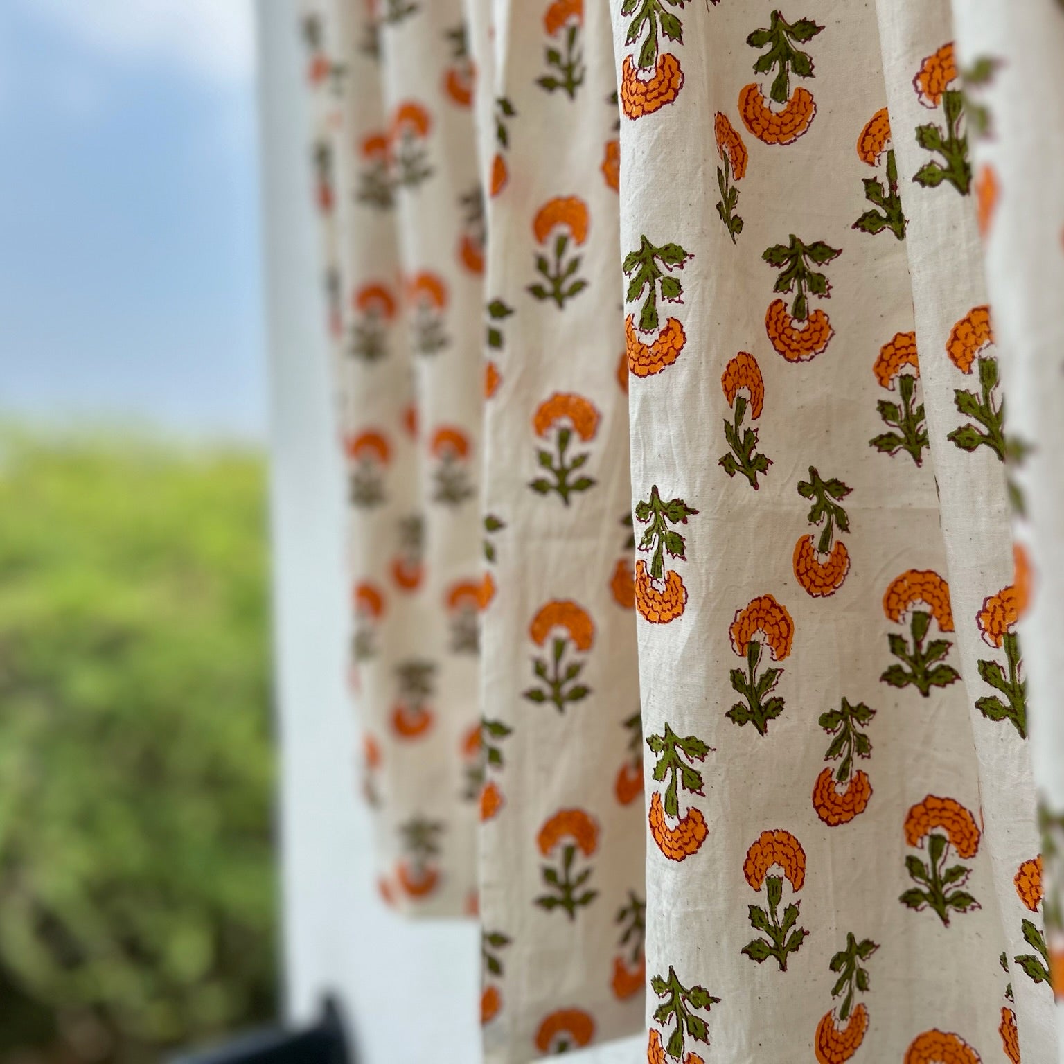 Curtains with a floral pattern in front of a blurred outdoor background