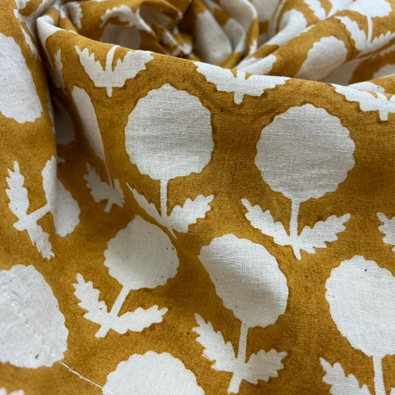 Close-up of fabric with white floral pattern on mustard yellow background