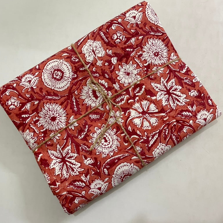 Folded fabric with red and white floral pattern on a light gray background