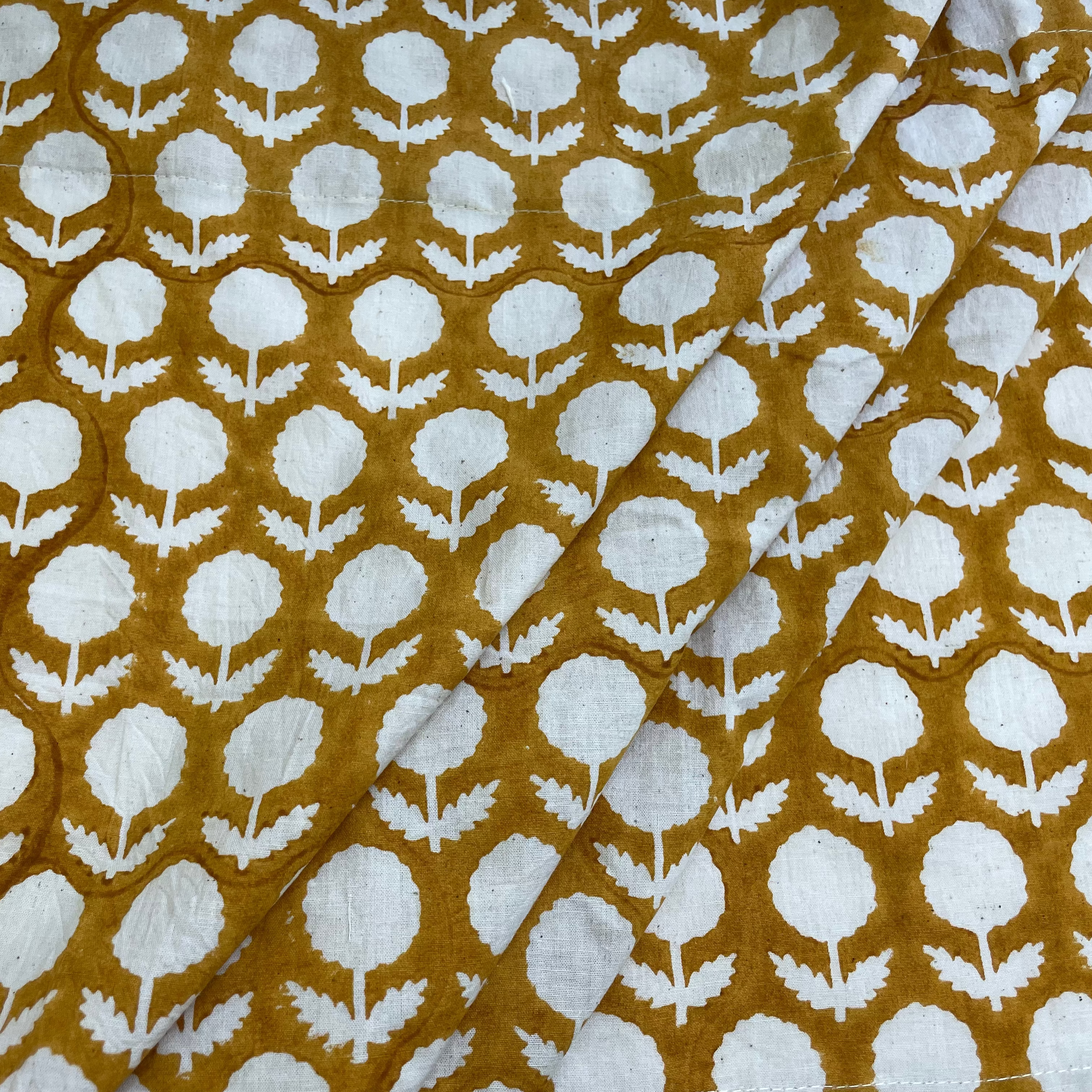Fabric with white floral pattern on a mustard yellow background