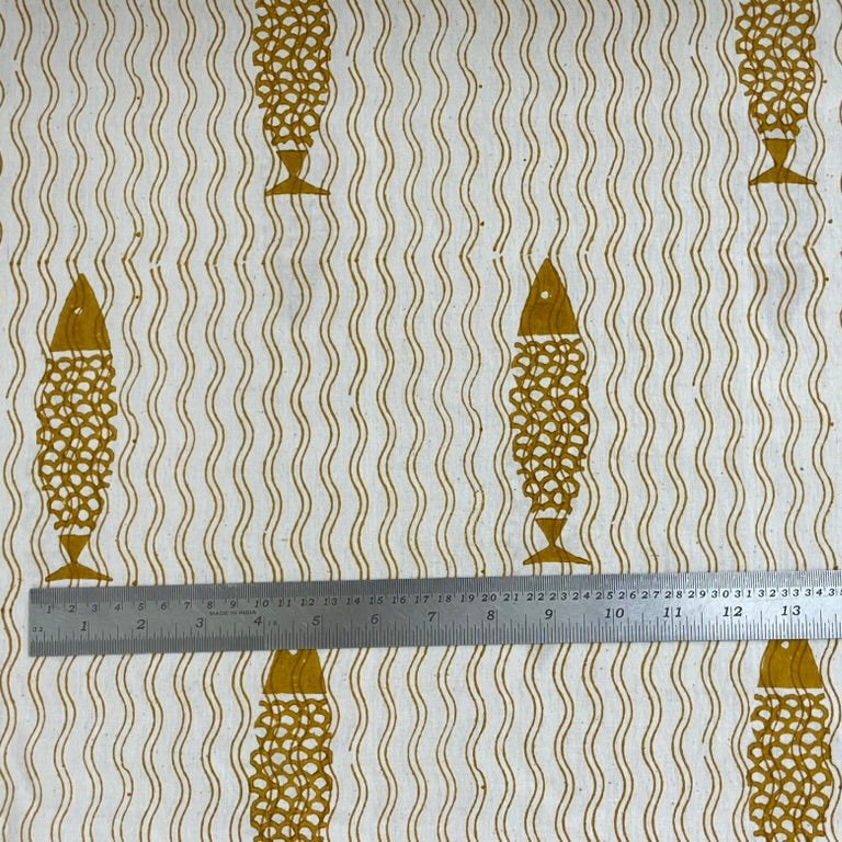 Fabric with gold fish pattern and wavy lines, measured by a ruler.