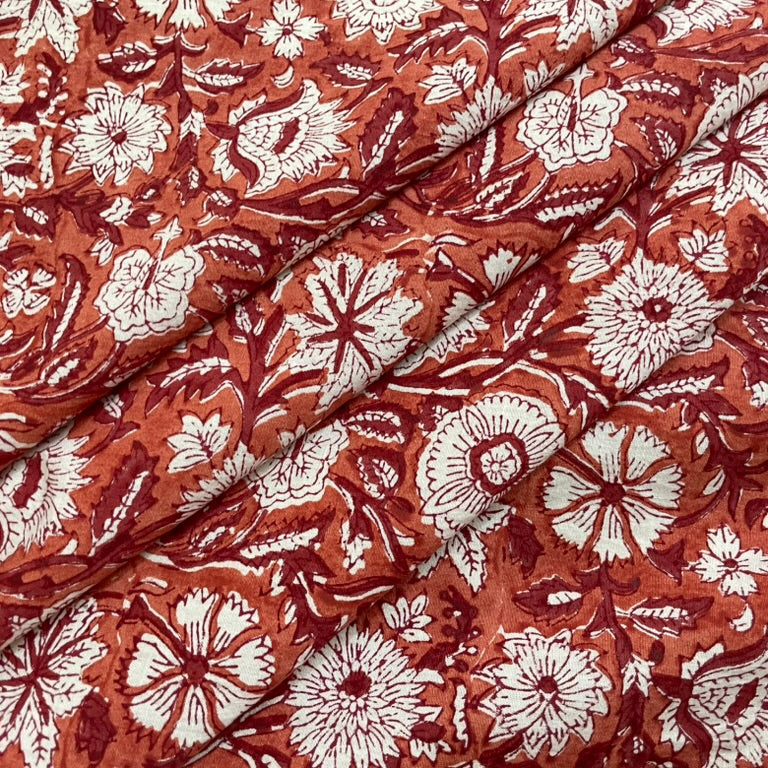 Floral patterned fabric with white flowers on a rust-colored background