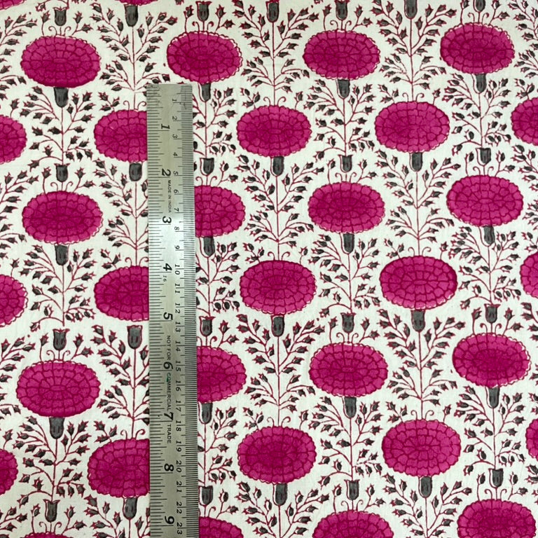 Fabric with a pink floral pattern and a ruler for scale on a white background