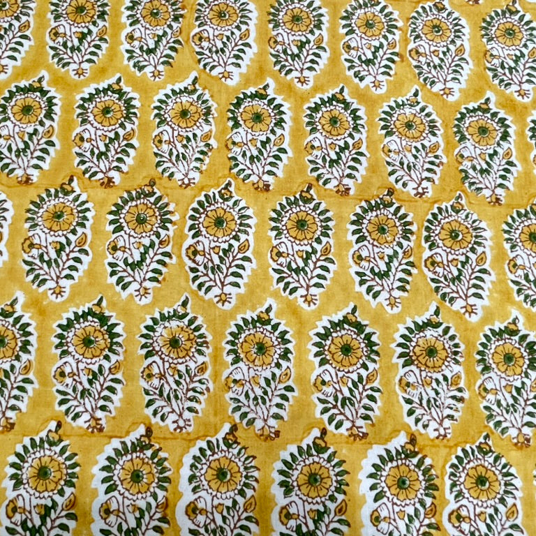 Patterned fabric with green and white floral design on a yellow background