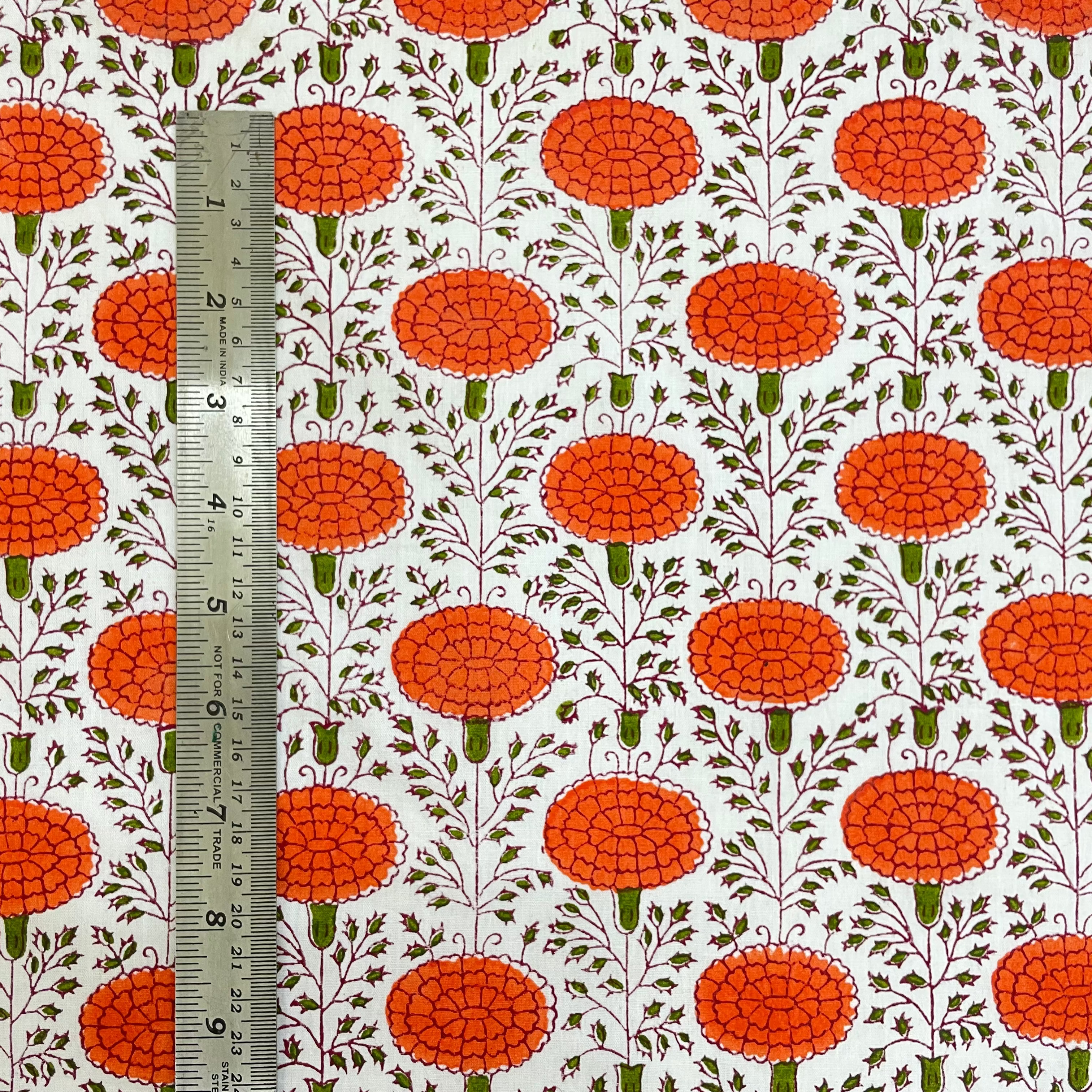 Fabric with red floral pattern and a ruler for scale on a white background