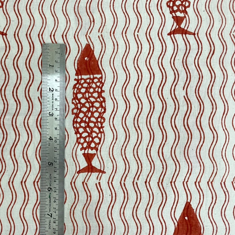 Fabric with red fish pattern and wavy lines, ruler for scale