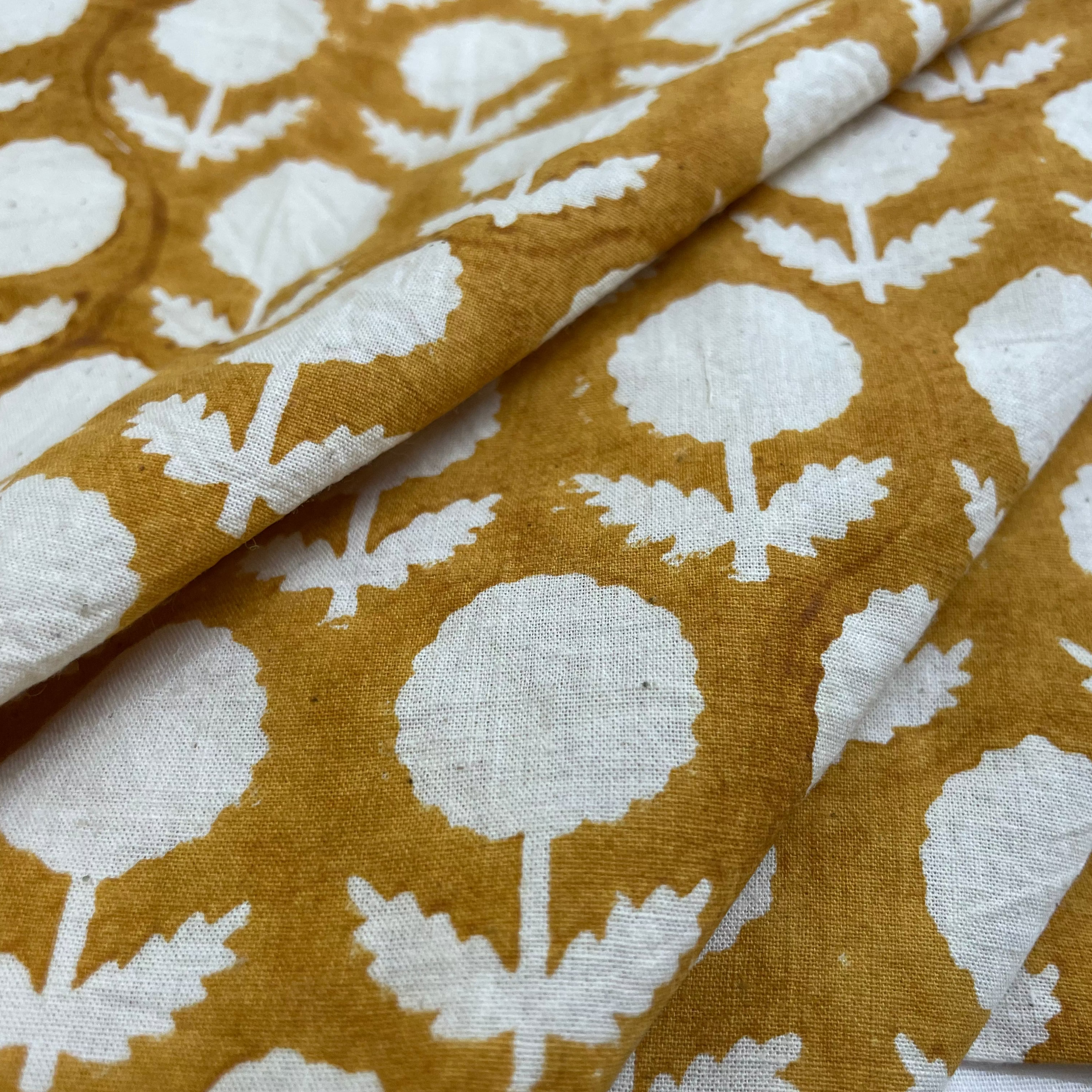 Fabric with white floral pattern on a mustard yellow background