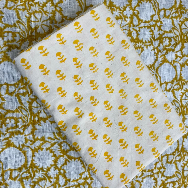 White fabric with yellow floral pattern on a textured green and white background