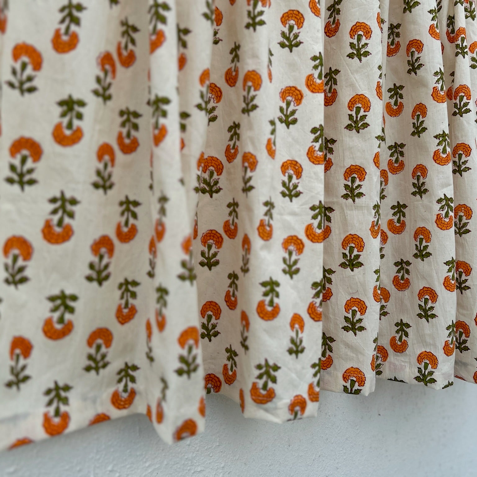 Curtain with orange and green floral pattern on a white background