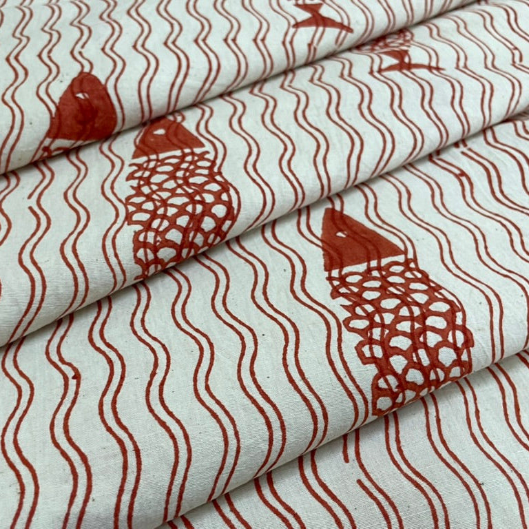 Folded fabric with red fish and wave pattern on a white background