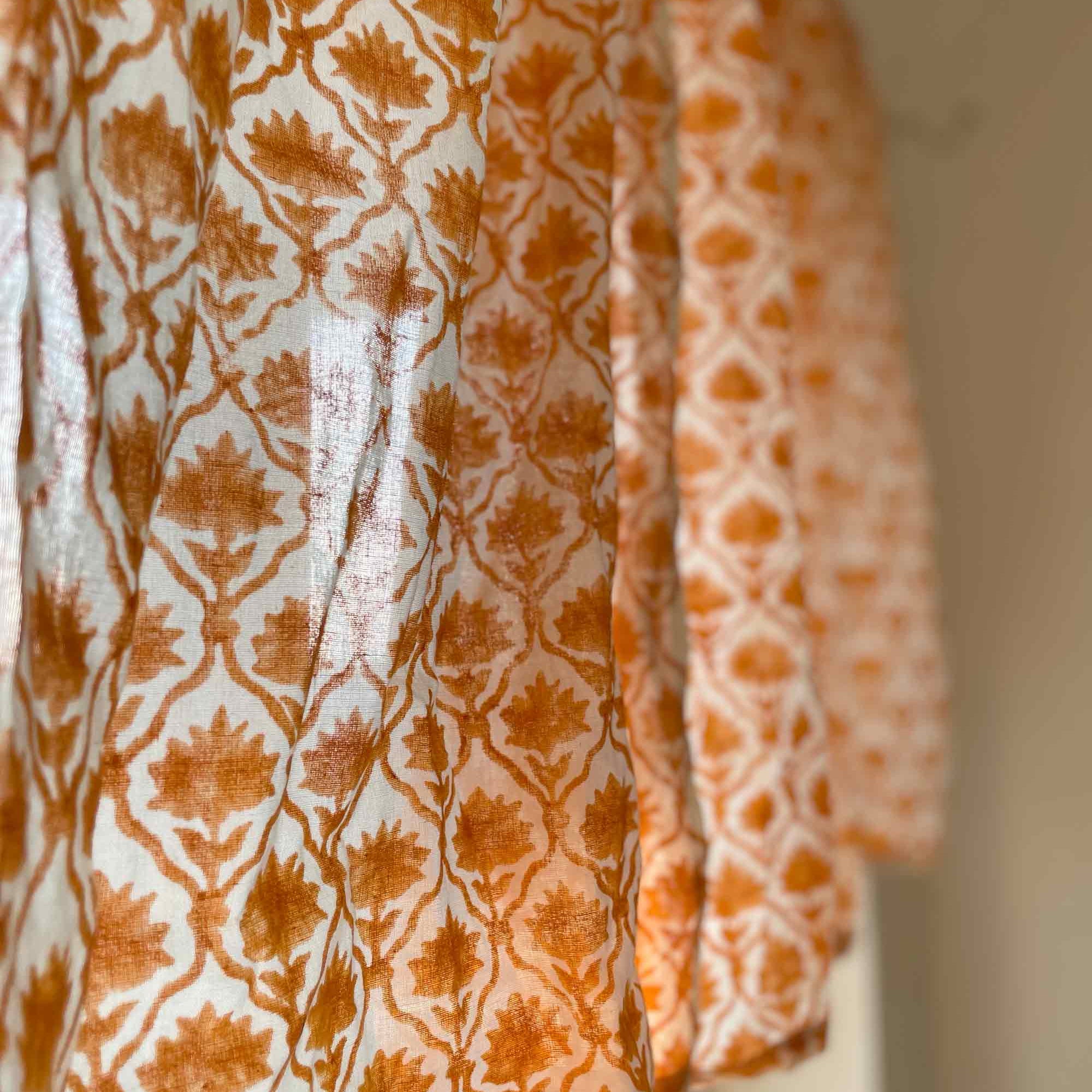 Two patterned fabrics hanging side by side with a neutral background