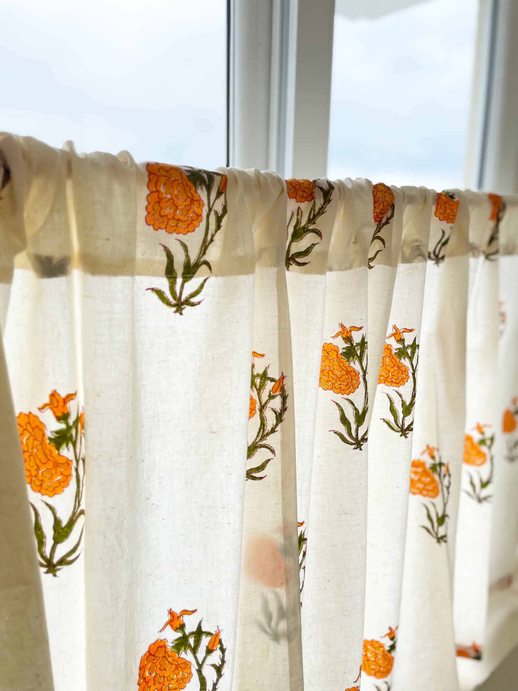 Rod pocket café curtain with orange marigold flowers and beige base, ideal for hiding storage spaces.
