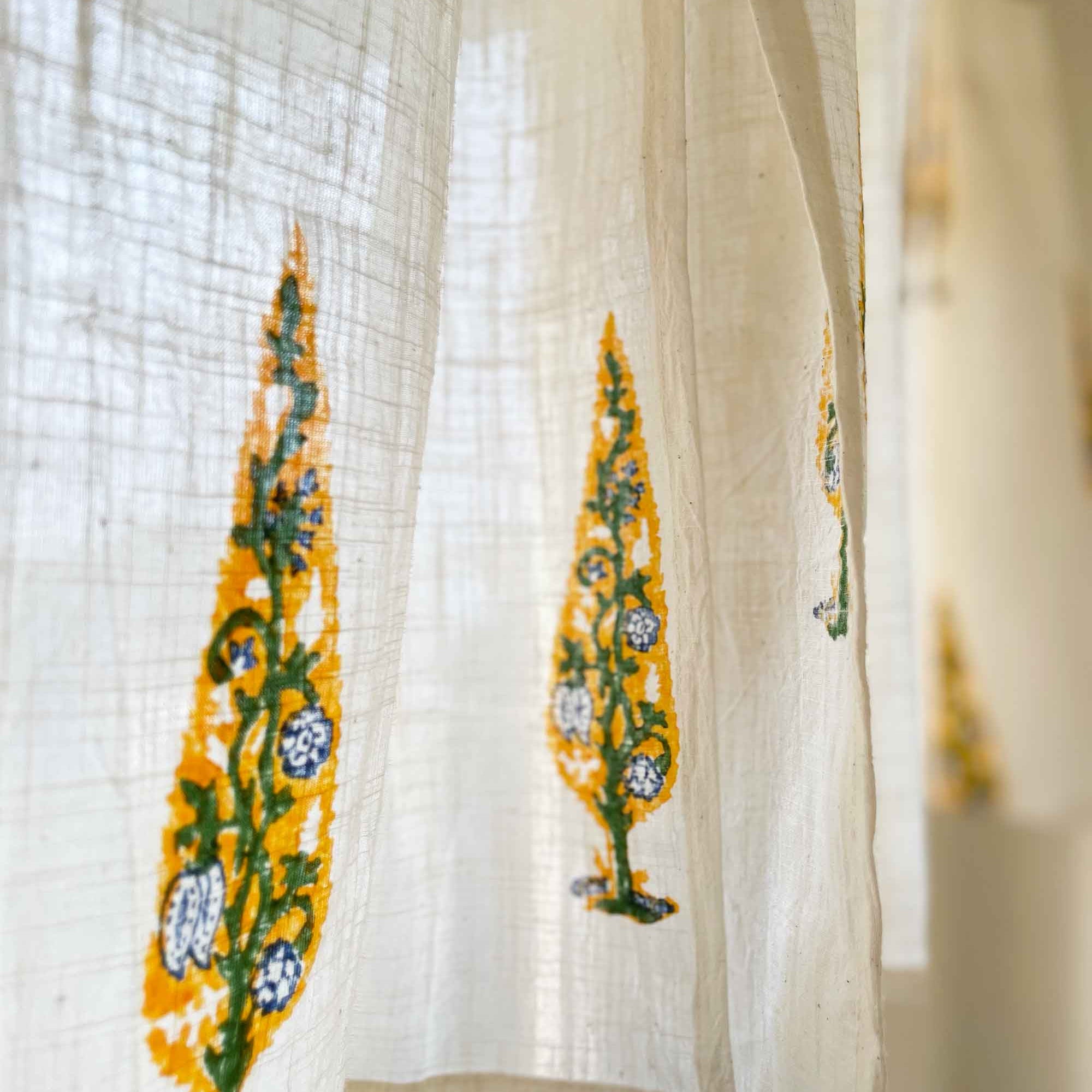 Sheer curtain with embroidered yellow and green patterns on a blurred background