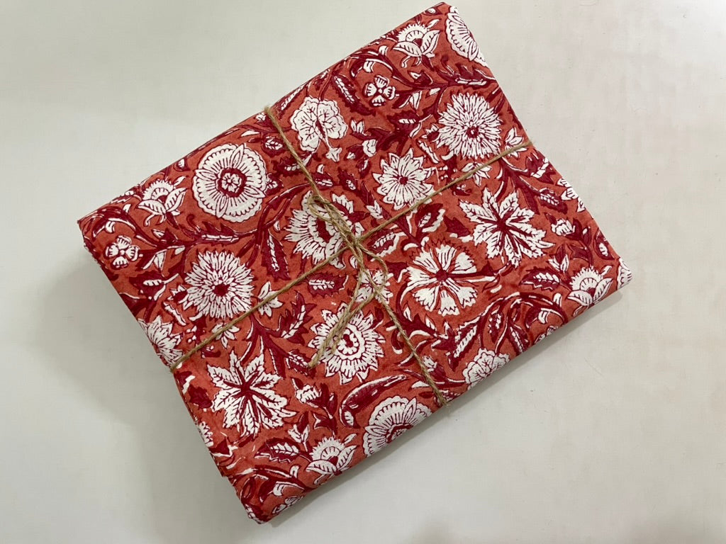 Folded fabric with red and white floral pattern on a light gray background