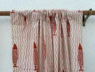 Curtain with red fish pattern on a wooden rod against a white wall