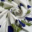 White fabric with a blue and green botanical block print pattern, styled in a spiral drape.
