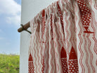 Red and white patterned fabric on a clothesline with a blue sky and greenery in the background