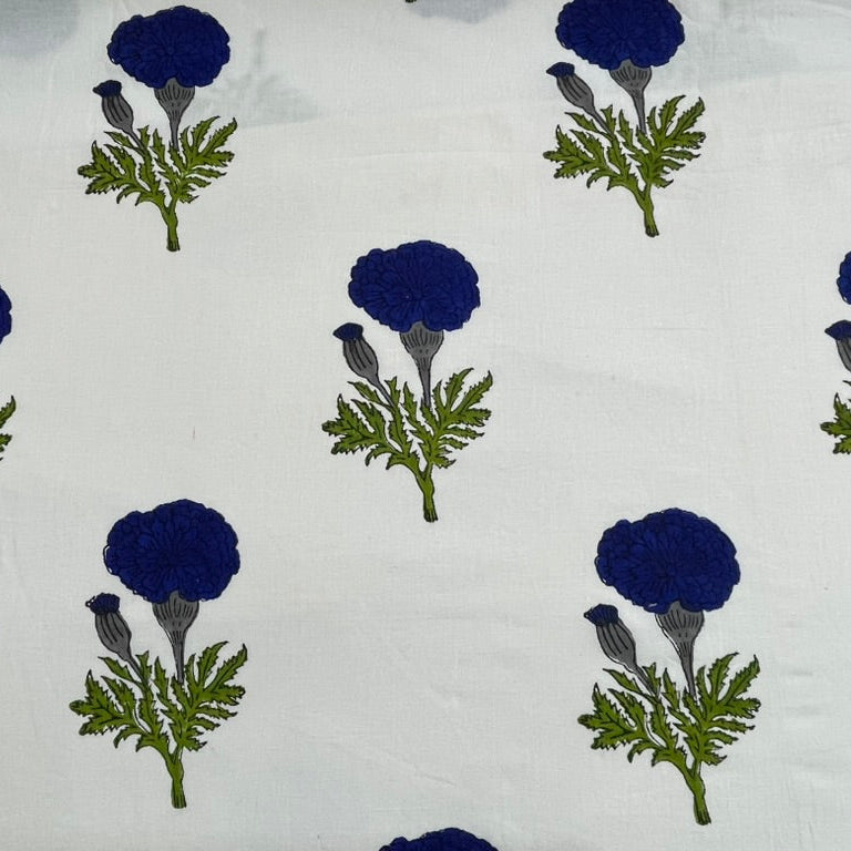 White fabric with a repeating block-print pattern of dark blue marigold flowers and green leaves.