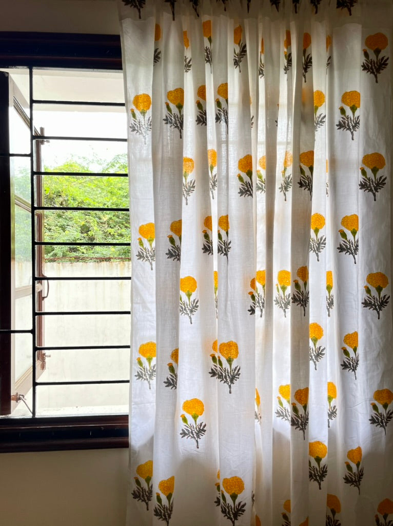 Curtain with yellow floral pattern in front of a window with bars