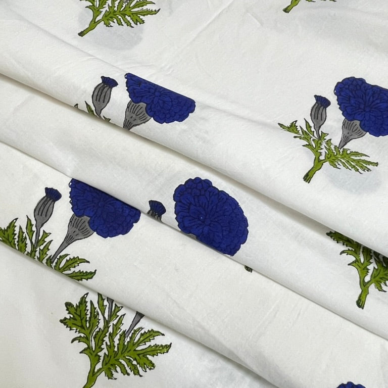 White fabric with a printed block pattern of blue poppy flowers and green leaves, shown in soft folds.