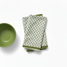 Green bowl and patterned green and white napkins on a white background